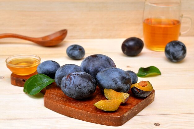 Ciruelas frescas y un vaso de jugo sobre la mesa