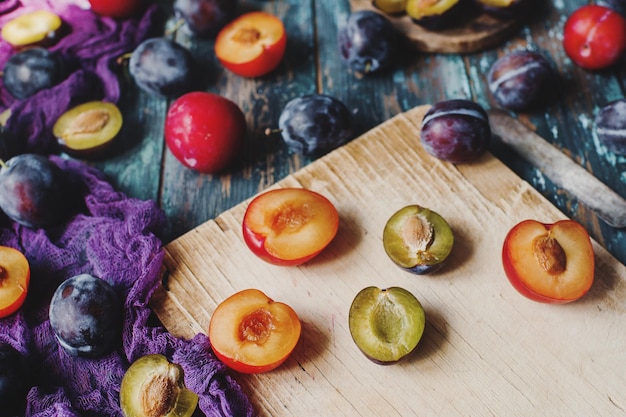 Foto ciruelas orgánicas frescas y rodajas de ciruela en tablero de madera y mesa de madera rústica cosecha de otoño frutas de temporada estilo de vida saludable enfoque selectivo