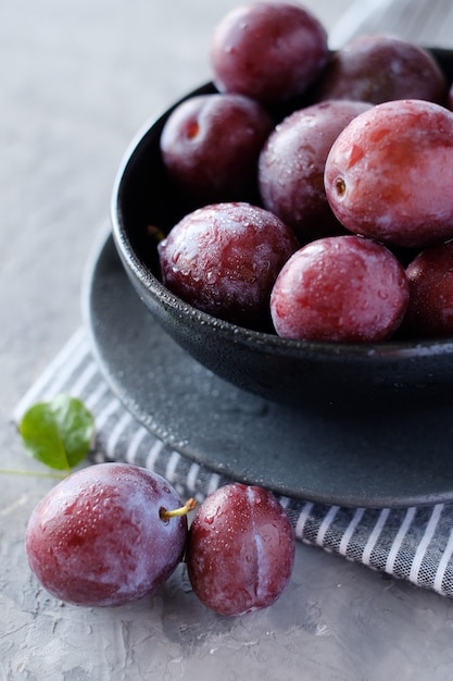 Foto ciruelas violetas frescas en el fondo de la mesa gris oscuro