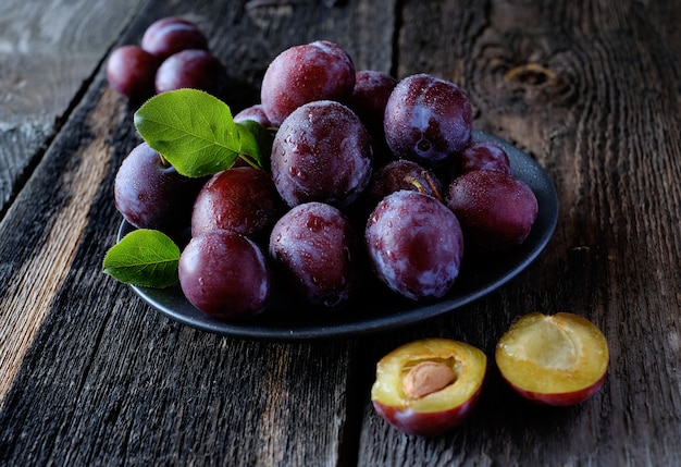 Ciruelas violetas frescas en el fondo de la mesa de madera oscura