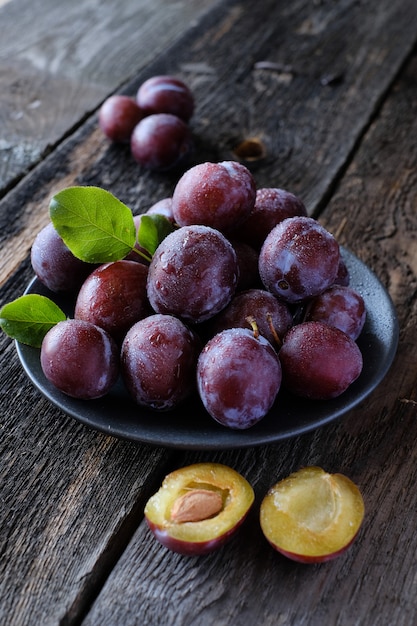 Ciruelas violetas frescas en el fondo de la mesa de madera oscura