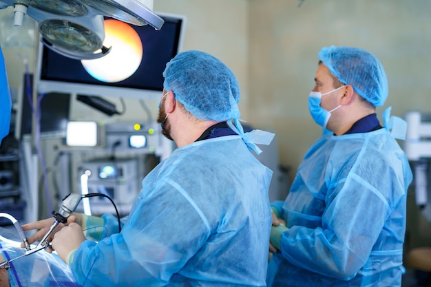 Cirugía de la columna. Grupo de cirujanos en quirófano con equipo quirúrgico. Doctor mirando la pantalla. Antecedentes médicos modernos