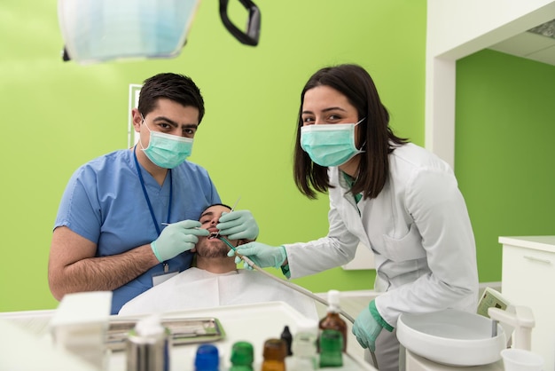 Cirugía en el consultorio del dentista El médico está trabajando en la boca del paciente con la ayuda de un asistente