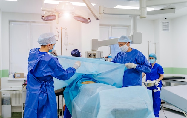 En cirugía Equipo médico que realiza la operación en el quirófano del hospital Trabajando con instrumentos quirúrgicos