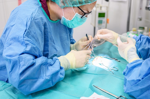 Foto cirujana en sala de operaciones, operando a un paciente.