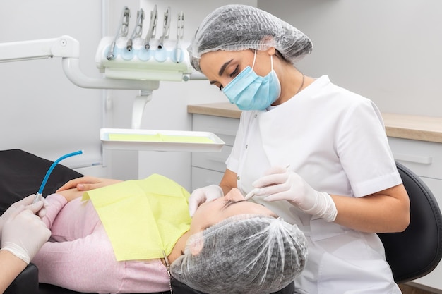 Cirujano dentista profesional y asistente que realiza una operación dental en una clínica con equipo moderno