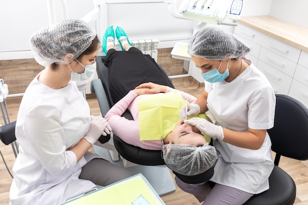 Cirujano dentista profesional y asistente que realiza una operación dental en una clínica con moderno