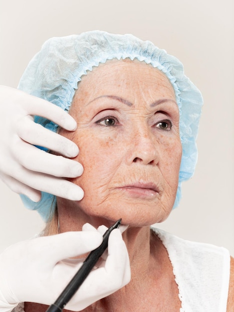 Foto cirujano haciendo chequeo de piel en mujer de mediana edad antes de la cirugía plástica