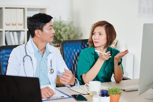 Cirujano joven serio hablando con el médico de su paciente