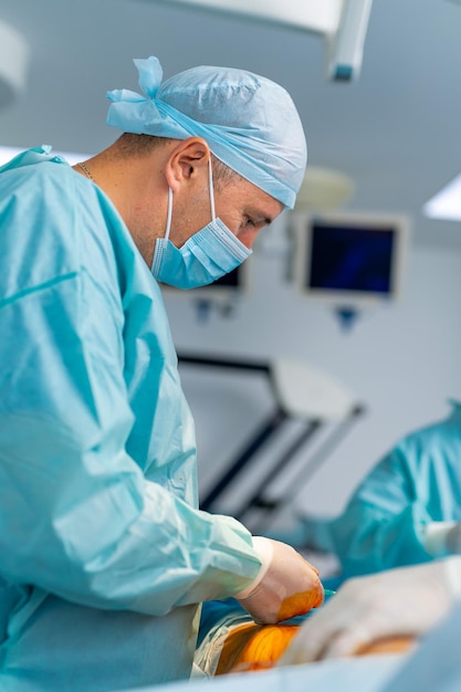 Cirujano masculino con gorra protectora y máscara de pie y preparando la operación Medic durante la operación Concepto de medicina