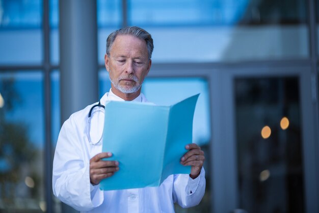 Foto cirujano masculino leyendo informe médico