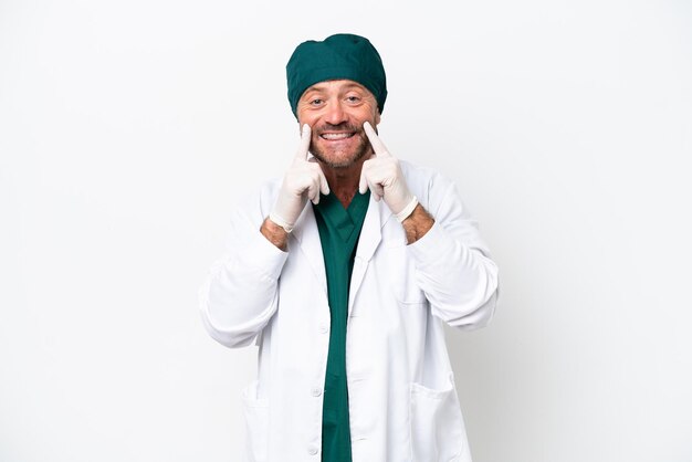 Cirujano de mediana edad con uniforme verde aislado de fondo blanco sonriendo con una expresión feliz y agradable