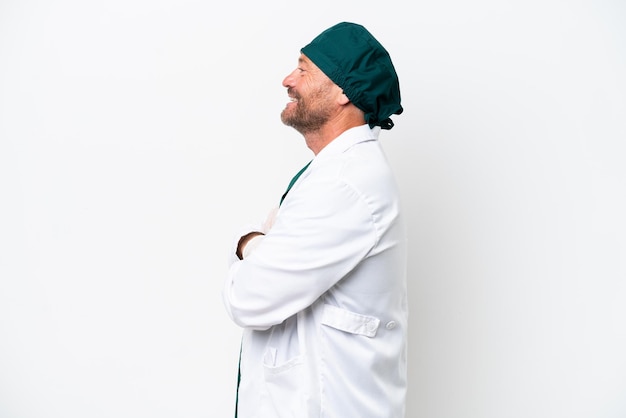 Cirujano de mediana edad en uniforme verde aislado sobre fondo blanco en posición lateral