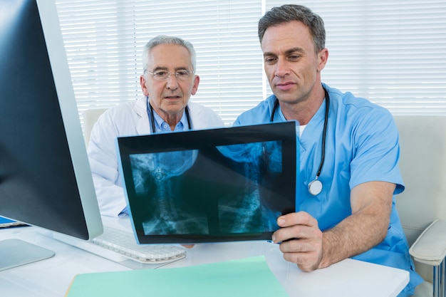 Cirujano y médico discutiendo informe de rayos x