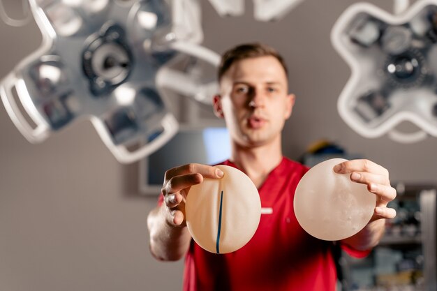 Foto el cirujano muestra diferentes tipos de implantes de silicona. cirugía de aumento de senos.