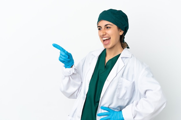 Cirujano mujer caucásica aislada sobre fondo blanco apuntando con el dedo hacia un lado y presentando un producto