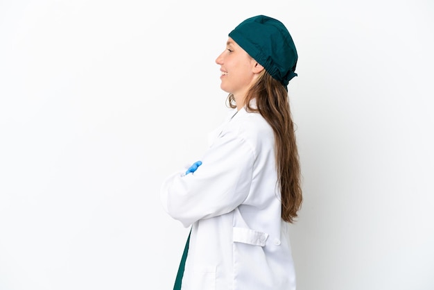 Foto cirujano mujer caucásica en uniforme verde aislado sobre fondo blanco en posición lateral