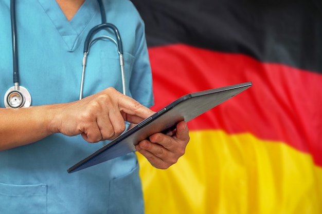 Cirujano o médico con una tableta digital en el fondo de la bandera de Alemania