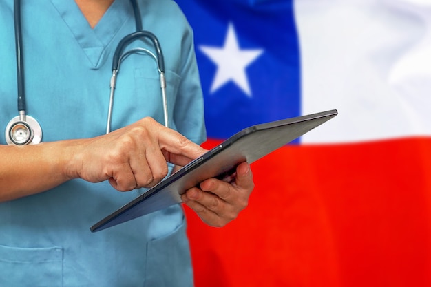 Cirujano o médico con una tableta digital en el fondo de la bandera de Chile