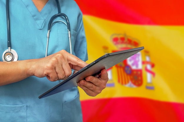 Cirujano o médico con una tableta digital en el fondo de la bandera de España