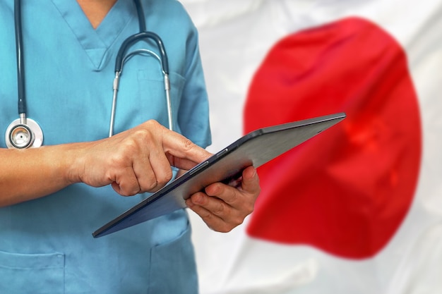 Cirujano o médico con una tableta digital en el fondo de la bandera de Japón