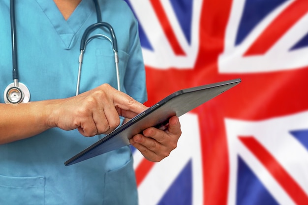 Cirujano o médico con una tableta digital en el fondo de la bandera del Reino Unido