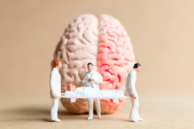 Cirujano de personas en miniatura habló con el paciente sobre las lesiones cerebrales. Concepto del Día Mundial del Accidente Cerebrovascular.