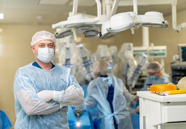 Cirujano profesional en uniforme azul y mascarilla protectora Retrato de médico con gafas de pie en quirófano