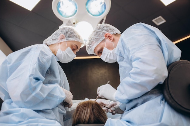 Cirujano y su asistente realizando cirugía estética en la nariz en el quirófano del hospital Rinoplastia de aumento de remodelación de la nariz