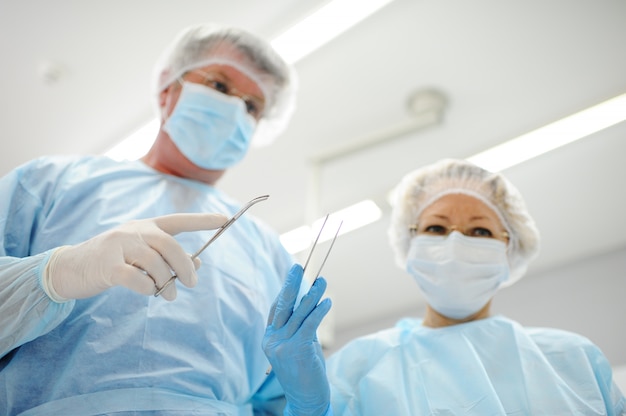 Cirujanos operan a un paciente en el fondo Lámpara quirúrgica