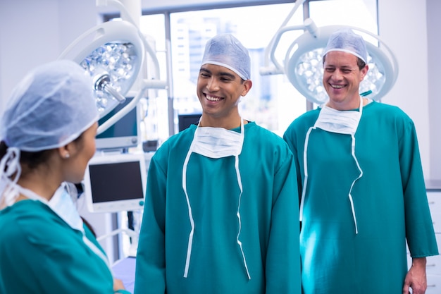 Cirujanos sonrientes que interactúan entre sí en la sala de operaciones