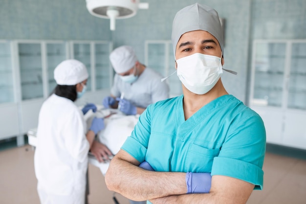 Cirurgiã com máscara cirúrgica na sala de cirurgia Jovem médico estagiário em uniforme cirúrgico