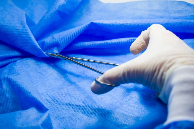Cirurgia forceps médicos mão no fundo azul estúdio filmar equipamento de operação
