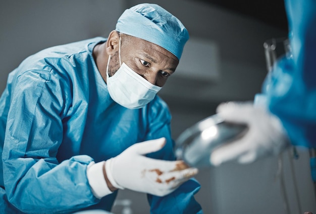 Foto cirurgia médica e teatro hospitalar com paciente e cirurgião negro para trabalho em equipe de emergência e confiança trabalhador médico profissional em epi para ferramentas que salvam vidas, assistência médica e seguro de saúde