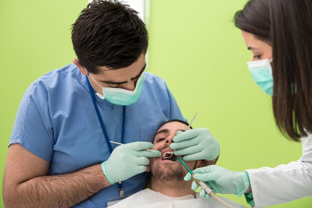 Cirurgia no consultório do dentista o médico está trabalhando na boca do paciente com a ajuda de um assistente