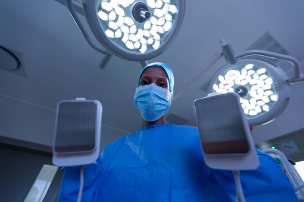 Foto cirurgiã usando desfibrilador na sala de cirurgia do hospital