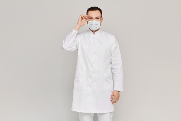 Foto cirurgião bonito ou médico posando em uma máscara facial e óculos de proteção