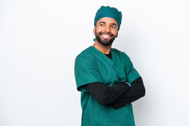 Cirurgião brasileiro de uniforme verde isolado em fundo branco com braços cruzados e feliz