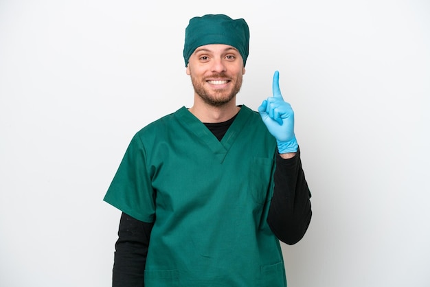 Cirurgião brasileiro de uniforme verde isolado no fundo branco apontando com o dedo indicador uma ótima ideia