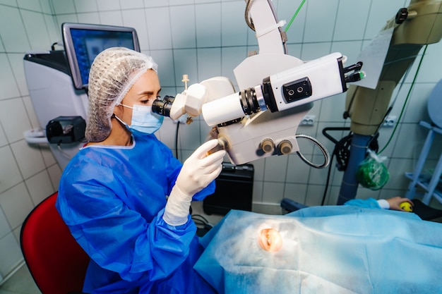 Foto cirurgião com sistema operacional de correção da visão a laser na sala de cirurgia