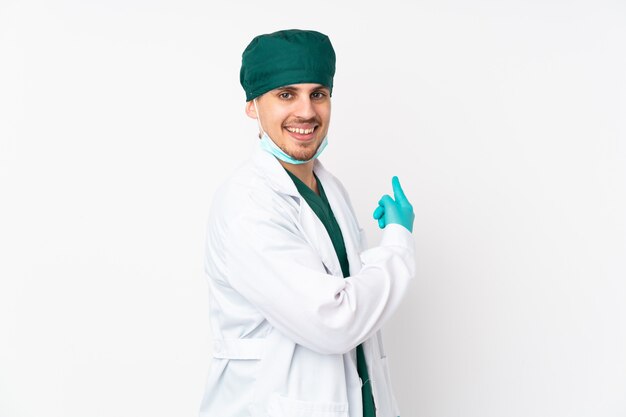 Cirurgião de uniforme verde em branco apontando para trás