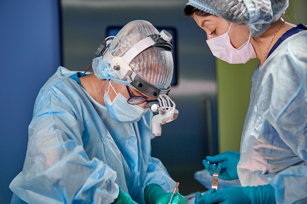 Cirurgião e seu assistente realizando cirurgia estética na sala de cirurgia do hospital