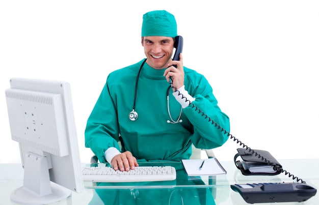 Foto cirurgião entusiástico no telefone que trabalha em um computador