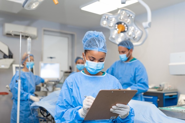 Foto cirurgião escrevendo na prancheta no anestesista da sala de operação escrevendo as atualizações