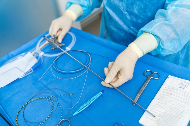 Cirurgião masculino em pé perto da mesa com instrumentos e médico trabalhando durante a operação Conceito de medicina