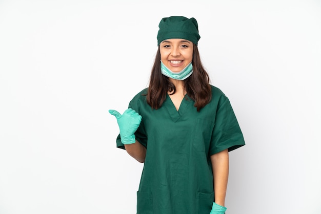 Cirurgião mulher de uniforme verde na parede branca, apontando para o lado