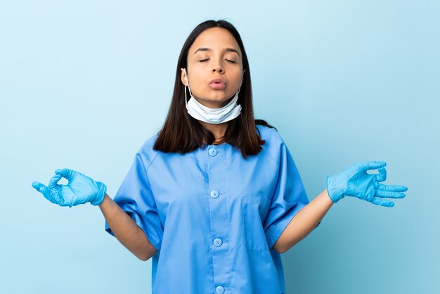 Cirurgião mulher isolado parede azul em pose de zen