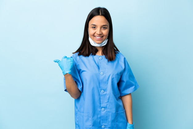 Foto cirurgião mulher parede azul apontando para o lado