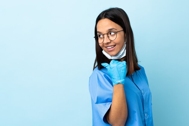 Cirurgião mulher parede azul apontando para o lado