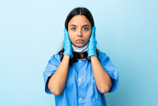 Cirurgião mulher parede azul frustrada e cobrindo as orelhas